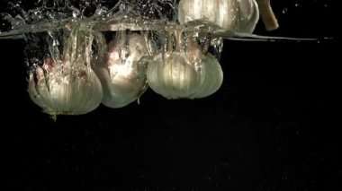 Taze sarımsak başları suyun altına düşer. 1000 fps 'de yüksek hızlı bir kamerayla çekildi. Yüksek kaliteli FullHD görüntüler