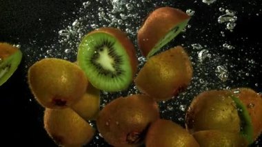 Dilimlenmiş kivi siyah arka planda suyun altına düşüyor. 1000 fps 'de yüksek hızlı bir kamerayla çekildi. Yüksek kaliteli FullHD görüntüler