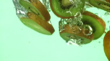 Dilimlenmiş kivi parçaları hafif arka planda suyun altına düşer. 1000 fps 'de yüksek hızlı bir kamerayla çekildi. Yüksek kaliteli FullHD görüntüler