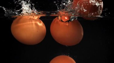 Siyah arka planda suyun altına düşen yumurtalar. 1000 fps 'de yüksek hızlı bir kamerayla çekildi. Yüksek kaliteli FullHD görüntüler