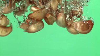 Sarımsak karanfilleri suyun altına düşer. 1000 fps 'de yüksek hızlı bir kamerayla çekildi. Yüksek kaliteli FullHD görüntüler