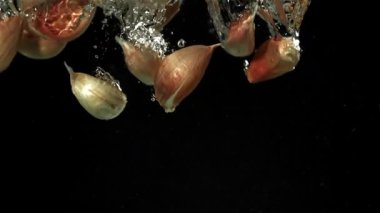 Sarımsak karanfilleri suyun altına düşer. 1000 fps 'de yüksek hızlı bir kamerayla çekildi. Yüksek kaliteli FullHD görüntüler