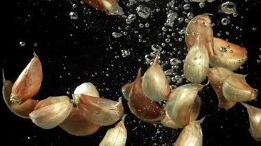Sarımsak karanfilleri suyun altına düşer. 1000 fps 'de yüksek hızlı bir kamerayla çekildi. Yüksek kaliteli FullHD görüntüler