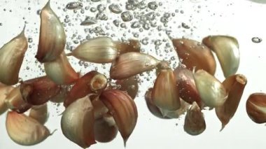 Sarımsak karanfilleri suyun altına düşer. 1000 fps 'de yüksek hızlı bir kamerayla çekildi. Yüksek kaliteli FullHD görüntüler