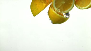 Limon dilimleri beyaz arka planda suyun altına düşüyor. 1000 fps 'de yüksek hızlı bir kamerayla çekildi. Yüksek kaliteli FullHD görüntüler