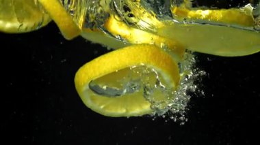 Limon dilimleri siyah arka planda suyun altına düşüyor. 1000 fps 'de yüksek hızlı bir kamerayla çekildi. Yüksek kaliteli FullHD görüntüler