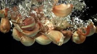 Sarımsak karanfilleri suyun altına düşer. 1000 fps 'de yüksek hızlı bir kamerayla çekildi. Yüksek kaliteli FullHD görüntüler