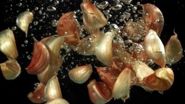 Sarımsak karanfilleri suyun altına düşer. 1000 fps 'de yüksek hızlı bir kamerayla çekildi. Yüksek kaliteli FullHD görüntüler