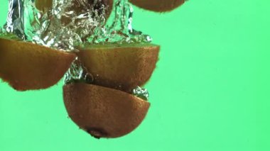 Dilimlenmiş kivi parçaları hafif arka planda suyun altına düşer. 1000 fps 'de yüksek hızlı bir kamerayla çekildi. Yüksek kaliteli FullHD görüntüler