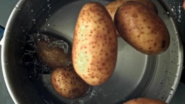 Patatesler bir tencere suya düşer. Yukarıdan bak. 1000 fps 'de yüksek hızlı bir kamerayla çekildi. Yüksek kaliteli FullHD görüntüler