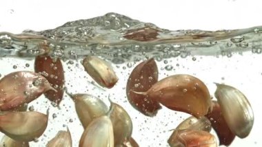 Sarımsak karanfilleri suyun altına düşer. 1000 fps 'de yüksek hızlı bir kamerayla çekildi. Yüksek kaliteli FullHD görüntüler