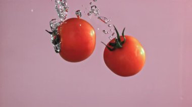Domatesler hafif arka planda suyun altına düşer. 1000 fps 'de yüksek hızlı bir kamerayla çekildi. Yüksek kaliteli FullHD görüntüler