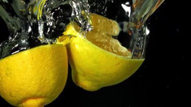 Limon dilimleri siyah arka planda suyun altına düşüyor. 1000 fps 'de yüksek hızlı bir kamerayla çekildi. Yüksek kaliteli FullHD görüntüler
