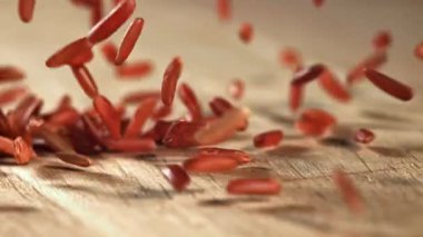 Kırmızı pirinç ahşap bir masaya düşer. 1000 fps 'de yüksek hızlı bir kamerayla çekildi. Yüksek kaliteli FullHD görüntüler