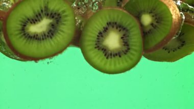 Dilimlenmiş kivi parçaları hafif arka planda suyun altına düşer. 1000 fps 'de yüksek hızlı bir kamerayla çekildi. Yüksek kaliteli FullHD görüntüler