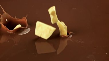 Çikolata Süper yavaş çekimde, Beyaz Çikolata Süt Sıvısına Düşüyor. 1000 fps 'de yüksek hızlı bir kamerayla çekildi. Yüksek kaliteli FullHD görüntüler