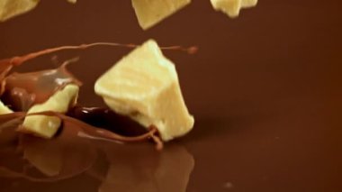 Çikolata Süper yavaş çekimde, Beyaz Çikolata Süt Sıvısına Düşüyor. 1000 fps 'de yüksek hızlı bir kamerayla çekildi. Yüksek kaliteli FullHD görüntüler