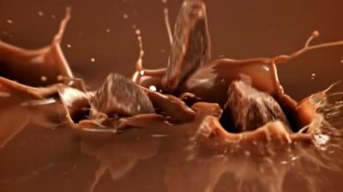 Süper yavaş çekimde siyah çikolata parçaları sıvı çikolatanın içine düşer. 1000 fps 'de yüksek hızlı bir kamerayla çekildi. Yüksek kaliteli FullHD görüntüler