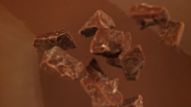 Süper yavaş çekimde siyah çikolata parçaları sıvı çikolatanın içine düşer. 1000 fps 'de yüksek hızlı bir kamerayla çekildi. Yüksek kaliteli FullHD görüntüler