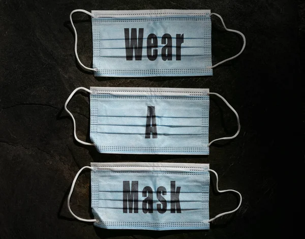 Blue surgical facemasks with Wear A Mask text, on dark background