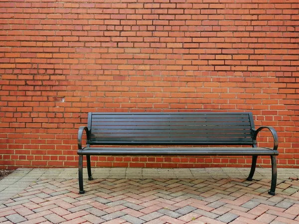 Een Lege Metalen Parkbank Voor Een Lege Bakstenen Muur — Stockfoto