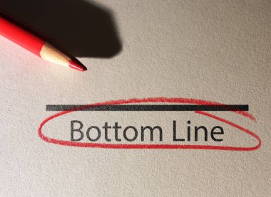 Bottom Line text circled in red pencil on textured paper surface                                clipart