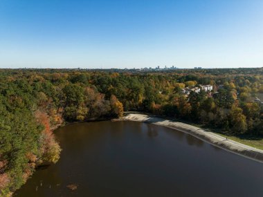 The walking trail along the dam at Lake Johnson city park in Raleigh with the skyline in the distance