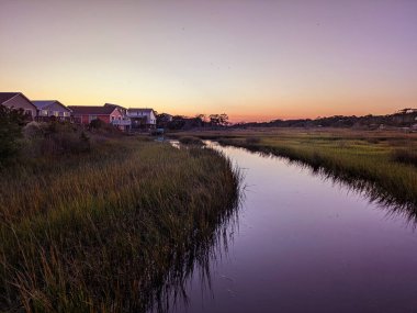Gün batımında Kuzey Carolina, Oak Adası 'ndaki rıhtım kanalı evleri ve bataklık.