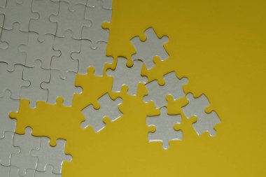 Sarı arkaplanda beyaz yapboz parçaları