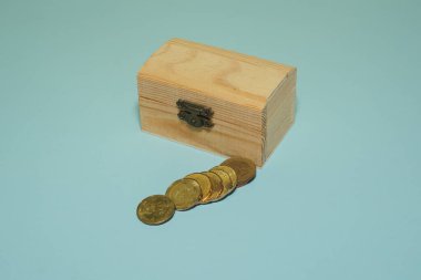 Mavi arka planda izole edilmiş bozuk paralarla ahşap kutu