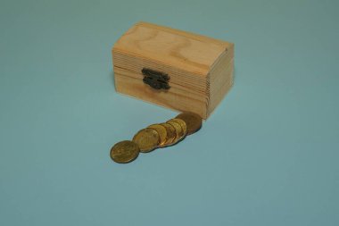 Mavi arka planda izole edilmiş bozuk paralarla ahşap kutu