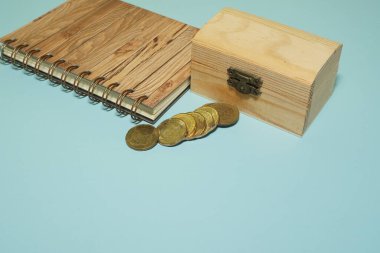 Mavi arka planda izole edilmiş bozuk paralarla ahşap kutu