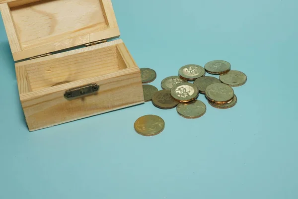 装有蓝色背景孤立硬币的木盒 — 图库照片