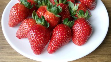 Beyaz bir tabakta taze olgun çileklerin yakın plan görüntüsü. 