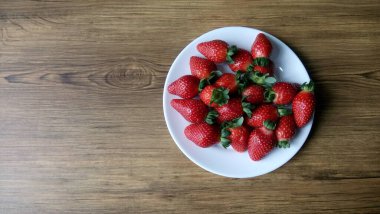 Beyaz bir tabakta taze olgun çileklerin yakın plan görüntüsü. 