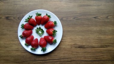 Beyaz bir tabakta taze olgun çileklerin yakın plan görüntüsü. 