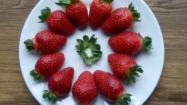 Beyaz bir tabakta taze olgun çileklerin yakın plan görüntüsü. 