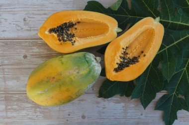 Papaya, ahşap arka planda yapraklı dilimler.