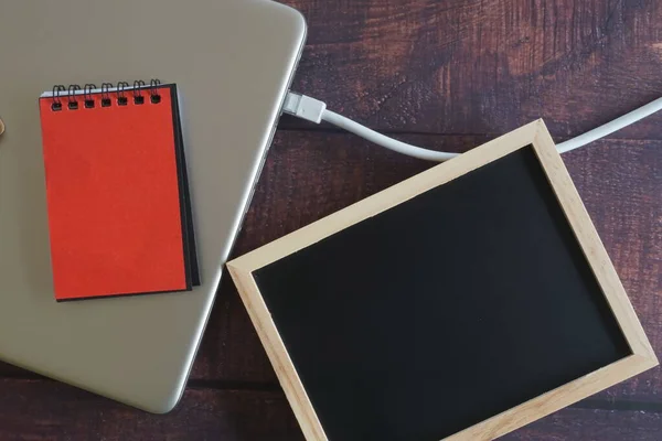 close up of laptop with internet cable and note book on wooden background