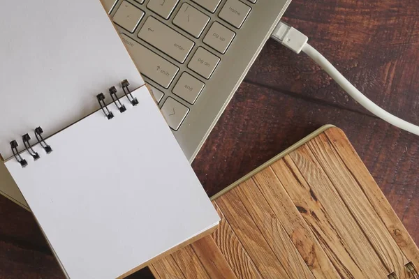 close up of laptop with internet cable and note book on wooden background