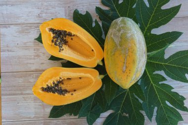 Papaya, ahşap arka planda yapraklı dilimler.