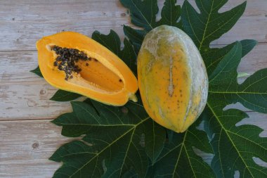 Papaya, ahşap arka planda yapraklı dilimler.
