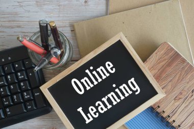 Bilgisayar klavyesi ve tahta zemin üzerine not defteri. Öğrenme kavramı.