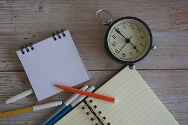 Masadaki çalar saat ve kırtasiye malzemeleri. Zaman yönetimi kavramı.