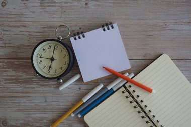 Masadaki çalar saat ve kırtasiye malzemeleri. Zaman yönetimi kavramı.