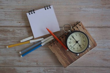 Masadaki çalar saat ve kırtasiye malzemeleri. Zaman yönetimi kavramı.