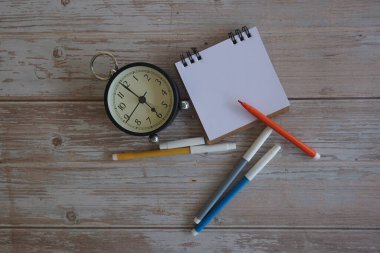 Masadaki çalar saat ve kırtasiye malzemeleri. Zaman yönetimi kavramı.
