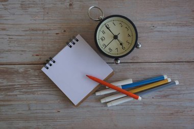 Masadaki çalar saat ve kırtasiye malzemeleri. Zaman yönetimi kavramı.