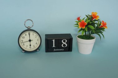 Mavi arka planda çiçek ve küp tarihi olan çalar saat. Ocak ayı konsepti.