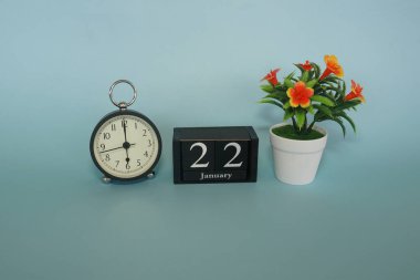Mavi arka planda çiçek ve küp tarihi olan çalar saat. Ocak ayı konsepti.